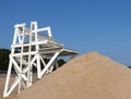 White lifeguard stand with sand pile in front and blue sky above Royalty Free Stock Photo
