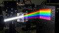 White light beam separates into a vibrant rainbow spectrum using a clear optical glass prism in a lab setting Royalty Free Stock Photo