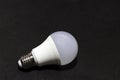 White light bulb on the black background. it is a glass bulb inserted into a lamp or a socket in ceiling.