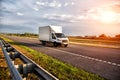 A white light-duty van isotherm transports products between cities on a country road in summer, sunset, industry Royalty Free Stock Photo