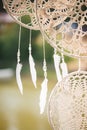 White light feathers hang on threads with transparent beads. Round dreamcatchers from macrame.