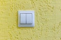 A white light switch on a yellow concrete wall.Turn the lights on or off Royalty Free Stock Photo