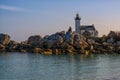 White lighthouse near rock formations on the shore of the sea under the beautiful sky Royalty Free Stock Photo