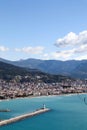 White lighthouse on the pier in Alanya port in Turkey surrounded by azure water of mediterranean sea