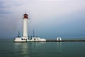 White lighthouse with a red tip in the sea. Royalty Free Stock Photo