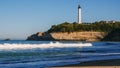 White lighthouse rises on a cliff, view from a sandy beach Royalty Free Stock Photo