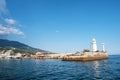 The white lighthouse tower at the entrance to the seaport of Yalta
