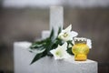 White lilies and candle on light grey granite tombstone outdoors. Funeral ceremony