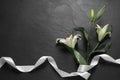 White lilies and ribbon on black table, flat lay with space for text. Funeral symbols Royalty Free Stock Photo