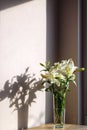 White lilies in a transparent vase on the background of the wall Royalty Free Stock Photo