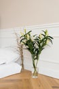 White lily flowers in a vase, tree branches in a vase. Details of the interior decor of the house