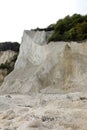 White limestone cliff being eroded by natural elements with plants s at risk of falling from the top Royalty Free Stock Photo