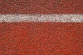 White line on the red running track at the stadium outside, close-up. Sports textured background top view. Finish, start concept Royalty Free Stock Photo