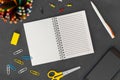 White line spiral paper notebook with mobile phone, pen, colored pencils, eraser, paper clips and scissors on dark background Royalty Free Stock Photo