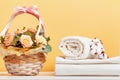 White linens, sheets and a roll of towels. Basket with flowers on the table