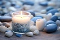 White lit aroma candle, heart and pebbles on beach. Generative AI