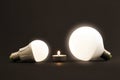 White little candle and LED electric bulbs on dark background. C