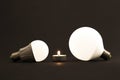 White little candle and LED electric bulbs on dark background. C