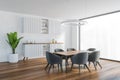 White living room with commode and table with grey chairs near window