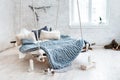 White loft interior in classic scandinavian style. Hanging bed suspended from the ceiling. Cozy large folded gray plaid