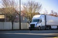 White long haul big rig semi truck transporting commercial cargo in dry van semi trailer running on the city street Royalty Free Stock Photo