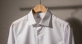 A white, long-sleeved dress shirt hangs on a wooden hanger. The shirt features a cri Royalty Free Stock Photo
