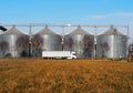 White long vehicle trailer truck in front of a grain storage bins