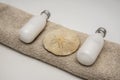 White lotion bottles towel and sand dollar Royalty Free Stock Photo