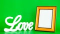 White LOVE sign and empty picture frame on green background