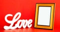 White LOVE sign and empty picture frame on red background