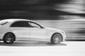 White luxury car is driving down the street at high speed. Abstract black and white photography of a fast moving blurred, white Royalty Free Stock Photo