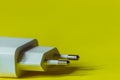 White mains charger close-up on a yellow background.