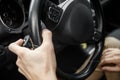 White male hand holds the steering wheel and toggles headlight switch inside the black car Royalty Free Stock Photo