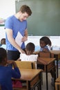 White male teacher helping schoolgirls at elementary school