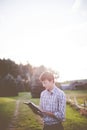 White male wearing a flannel shirt reading the bible under the bright rays of sunshine