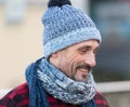 Portrait of smiling white guy on street. White male in winter knitted hat and scarf. Bearded man in blue-white hat and red jacket Royalty Free Stock Photo