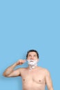 White man holds a toothbrush, shaving and looks up on blue background Royalty Free Stock Photo