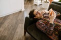 White man laughing and using mobile phone while resting on couch Royalty Free Stock Photo