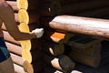 A white man manually covers a fragment of the verandah of a house made of a round log with a dark-skinned hostess Royalty Free Stock Photo