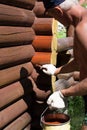 A white man manually covers the wooden house of a mistress with dark skin with a protective agent Royalty Free Stock Photo