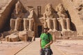 White Man Tourist in the Colossal Statues of Ramesses II seated on a throne near the entrance to the Great Temple at Abu Simbel Royalty Free Stock Photo