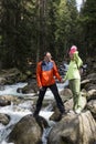 White man and woman standing on the rocks on the Bank of a mountain river in the spruce forest, people in nature