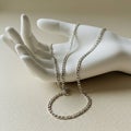 A white mannequin hand rests on a light beige surface, displaying a silver chain Royalty Free Stock Photo