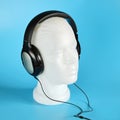 White mannequin head with musical stereo headphones, on blue background Royalty Free Stock Photo