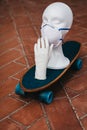 White Mannequin Head Wearing A Medical Face Mask On A Skateboard - The Concept Of Coronavirus