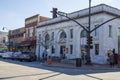 The white marble First National Bank building with tables and chairs on the red brick sidewalk, tall black light posts