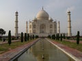 White marble mausoleum with four minarets dedicated to love seen from one of its fountains. Taj Mahal