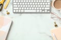 White marble office desk table with keyboard, coffee cup, beige paper notebooks, eye glasses. Flat lay, top view, copy space Royalty Free Stock Photo