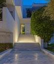 white marble pathway and stairs to modern house entrance through the garden