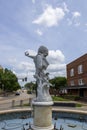 A white marble statue of Christopher Columbus at Columbus Plaza surrounded by red brick buildings and lush green trees